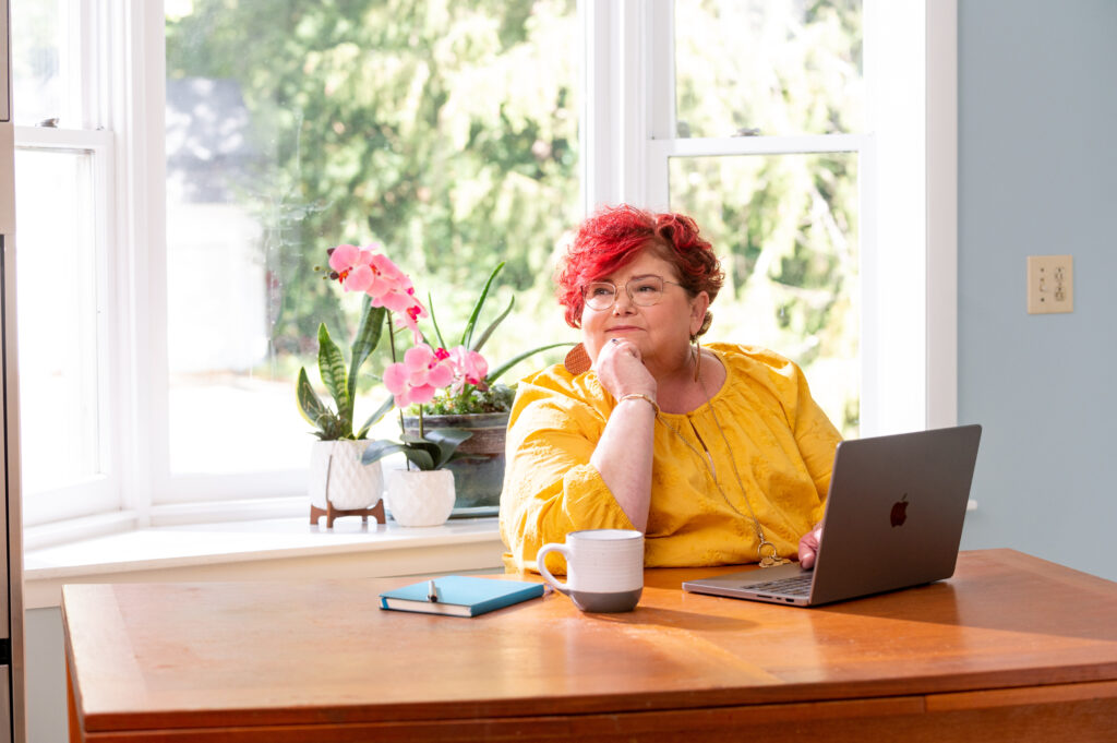 Women at desk and computer with bright windows behind her
